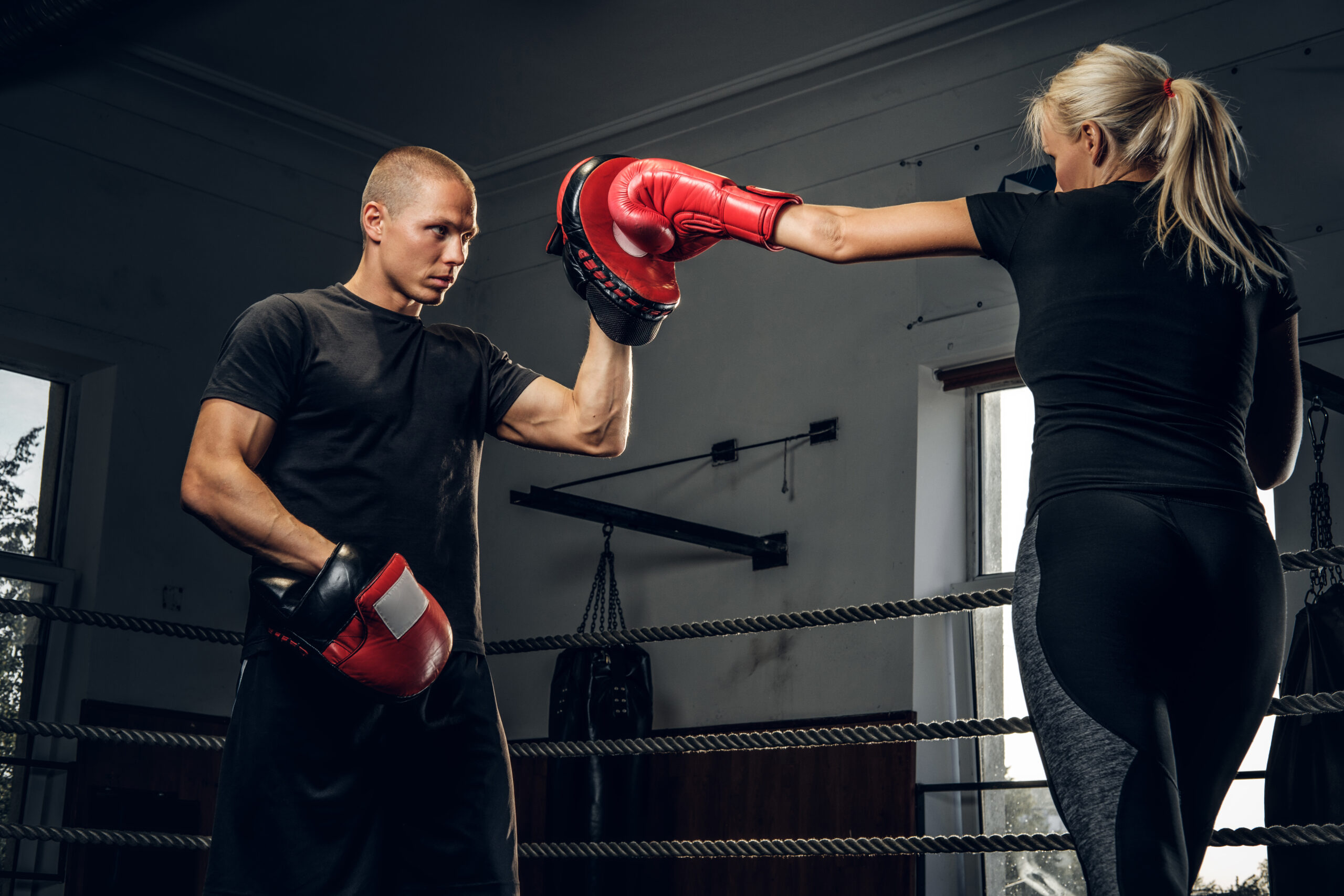 Blonde girl has a training with experienced boxer
